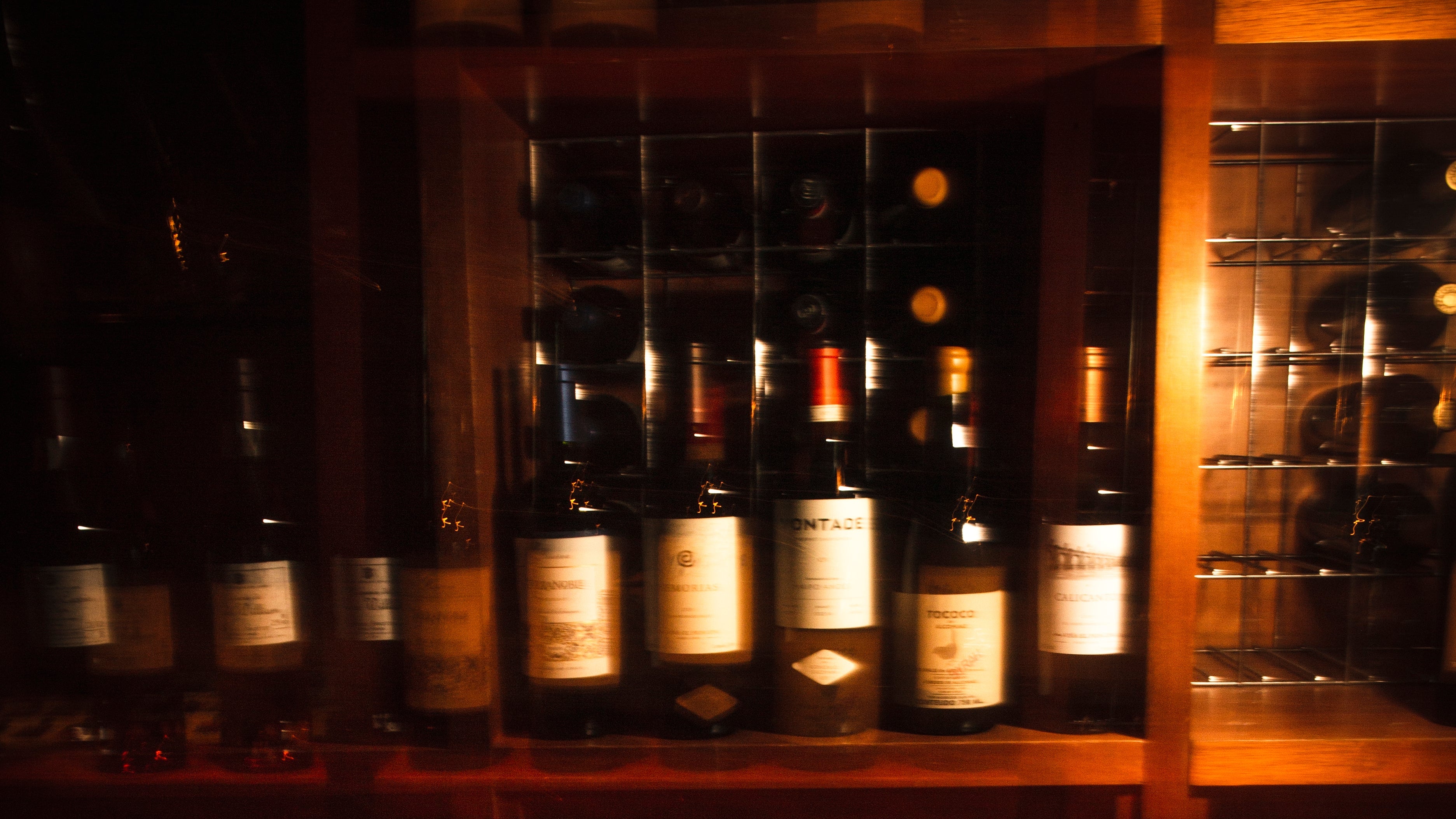 Garrafas de vinho deitadas nas prateleiras da adega da Enoteca La Tavola